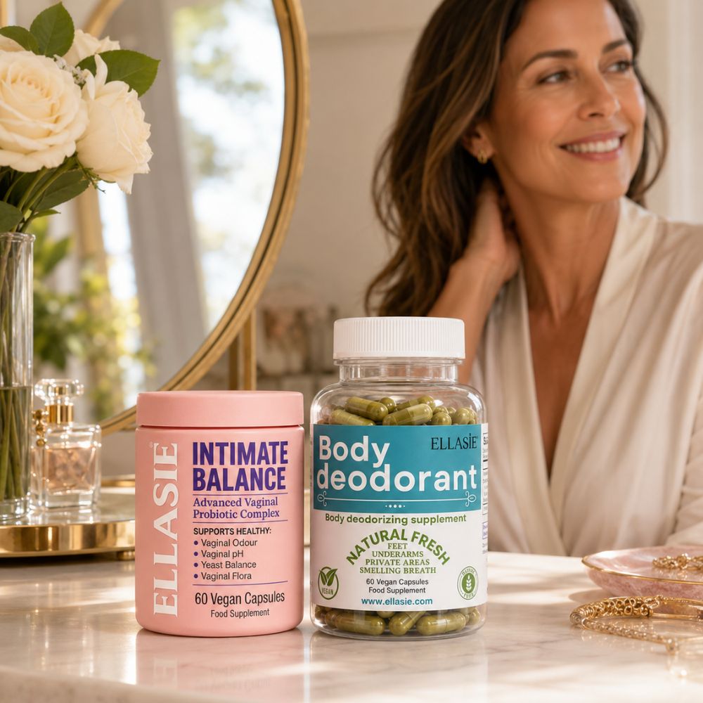 Two supplement bottles from ELLASiE on a bathroom counter: a pink tub labeled 'Intimate Balance' and a clear bottle labeled 'Body deodorant' with green capsules inside, with a smiling woman in a robe in the background.