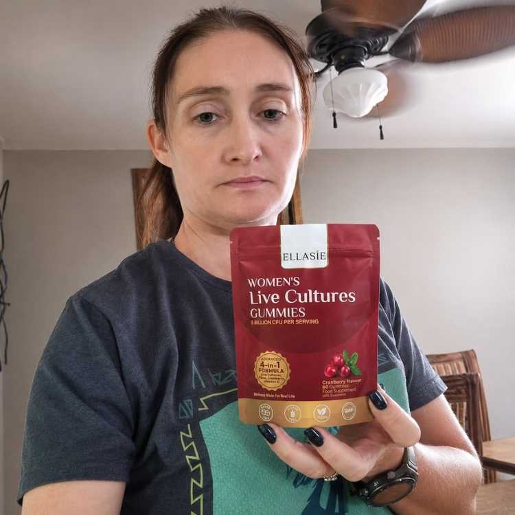 Woman holding a red package of Ellasie Women's Live Cultures Gummies in a room with a ceiling fan.