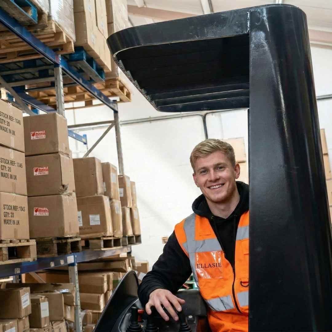 Person in an orange safety vest standing next to a forklift in a warehouse.