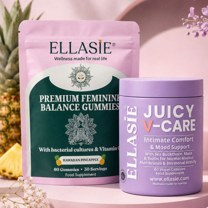 Two wellness products from ELLASIE arranged on a pink surface: a large pink stand-up pouch of Premium Feminine Balance Gummies and a lavender tub of Juicy V-Care intimate comfort capsules, with decorative flowers and pineapple edges in the background.