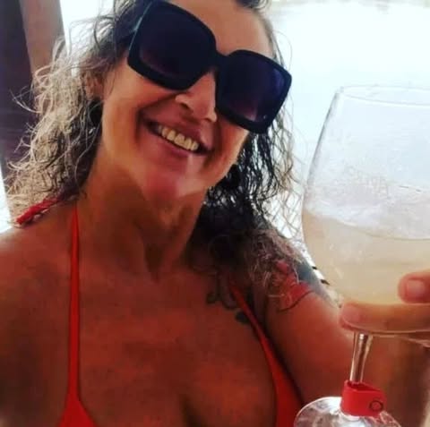 Person wearing sunglasses and a red bikini top, holding a drink.