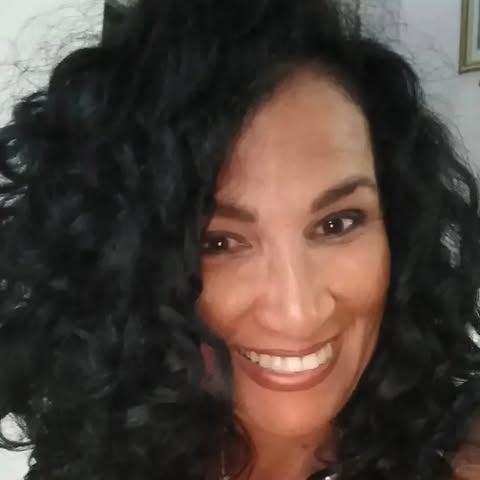 Woman with curly black hair smiling at the camera