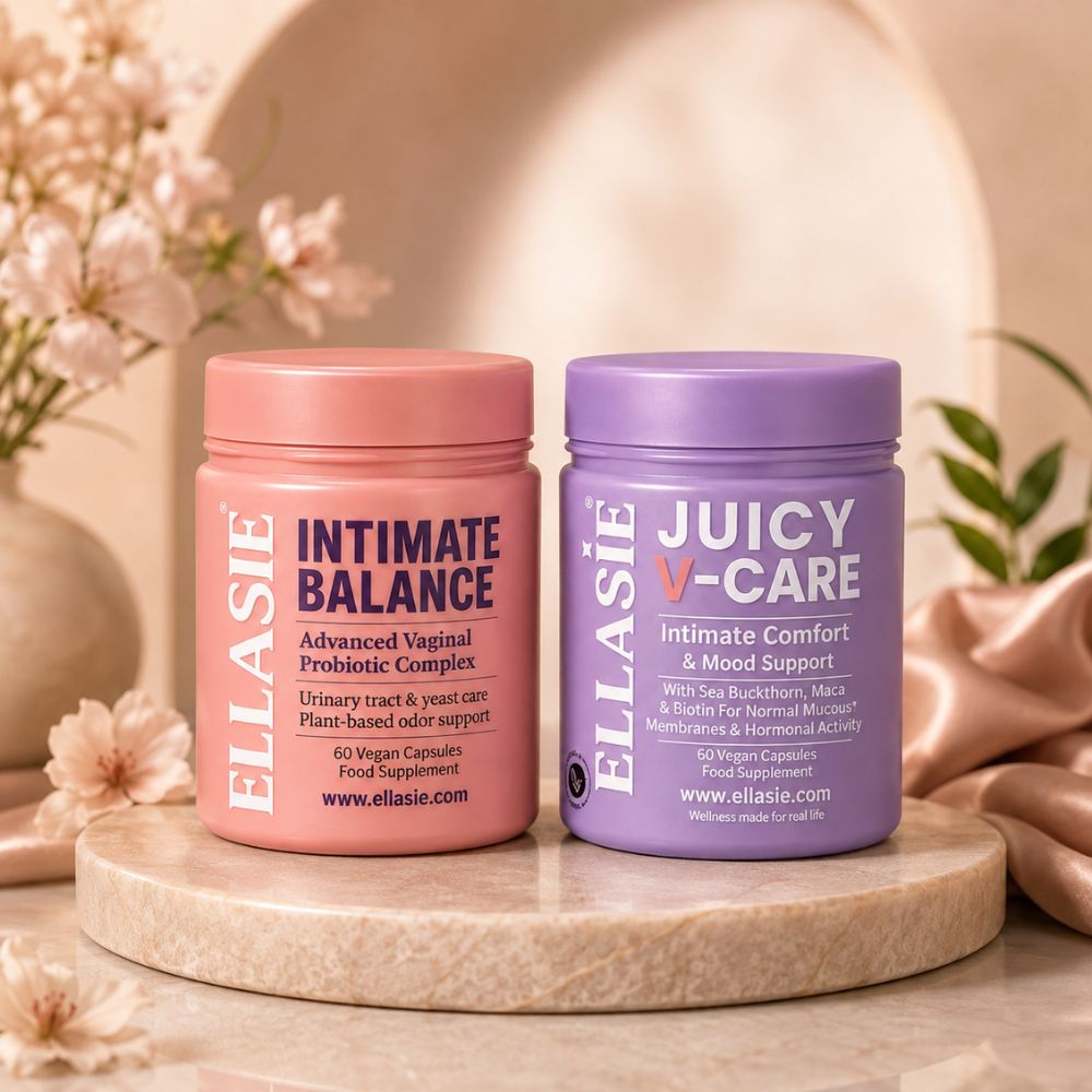 Two cylindrical supplement jars from ELLASIE displayed on a round stone pedestal. The left jar is pink with a coral-pink lid and reads 'INTIMATE BALANCE'.